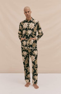 the model is wearing a black and gold floral pajama set